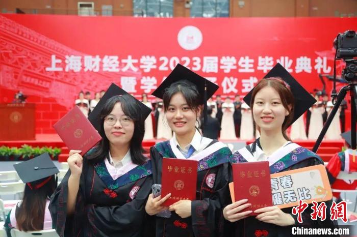 上海财经大学2023届毕业生手持毕业证书合影留念。　上海财经大学供图