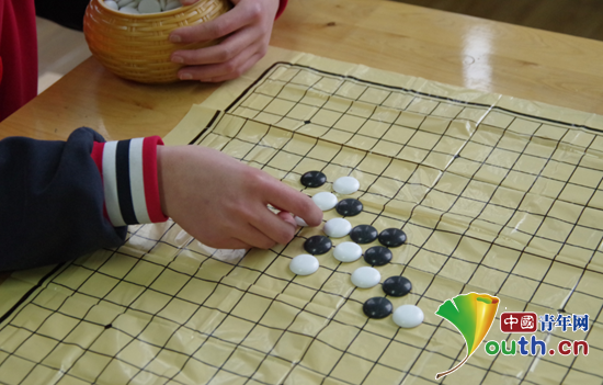图为参加五子棋比赛的选手正举棋落子。上海财经大学研支团 供图
